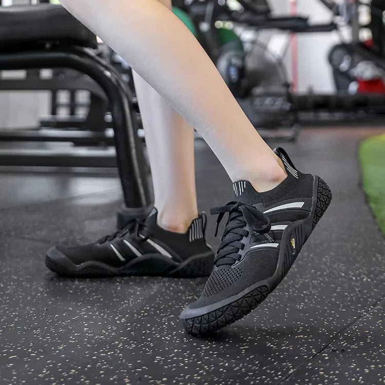 Black athletic sneakers with mesh upper, reflective stripes, and cushioned fit in gym setting