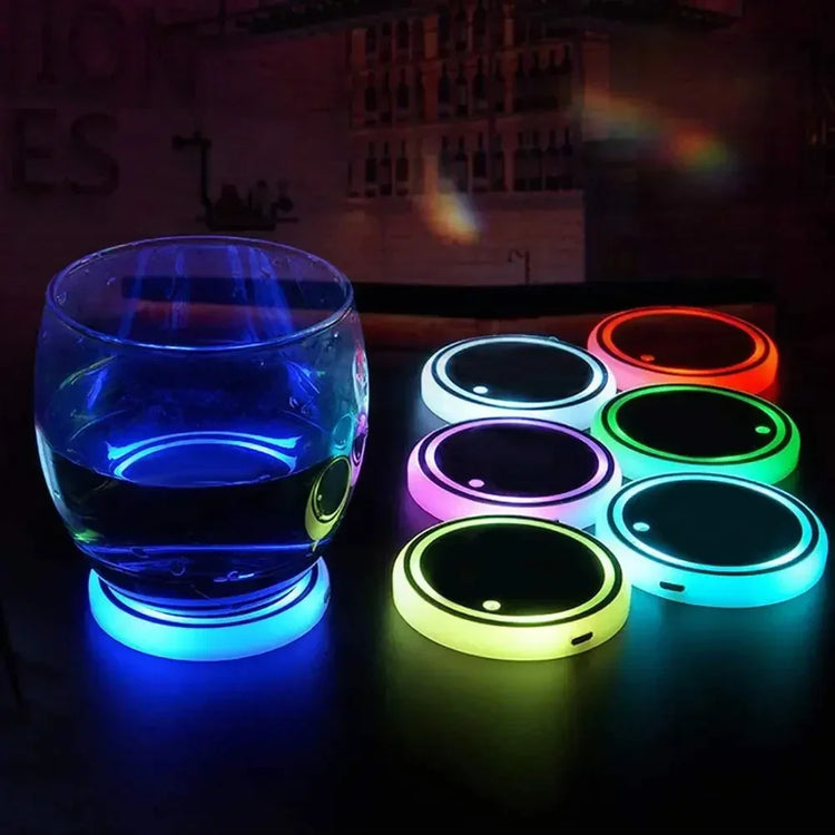 Round glass on blue LED light-up coaster with assorted colorful glowing drink coasters on table