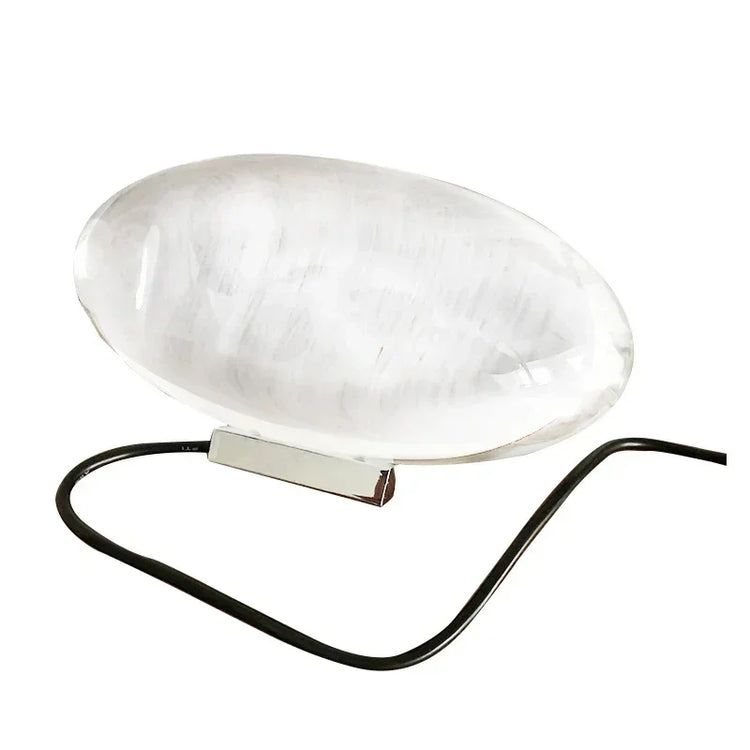 Futuristic clear acrylic oval lamp with sleek metal base and black cord, minimalist design