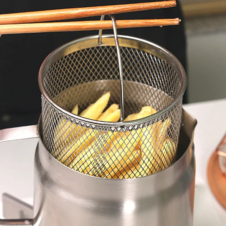 Stainless steel mesh basket with potato fries in a fryer, wooden chopsticks resting on top.