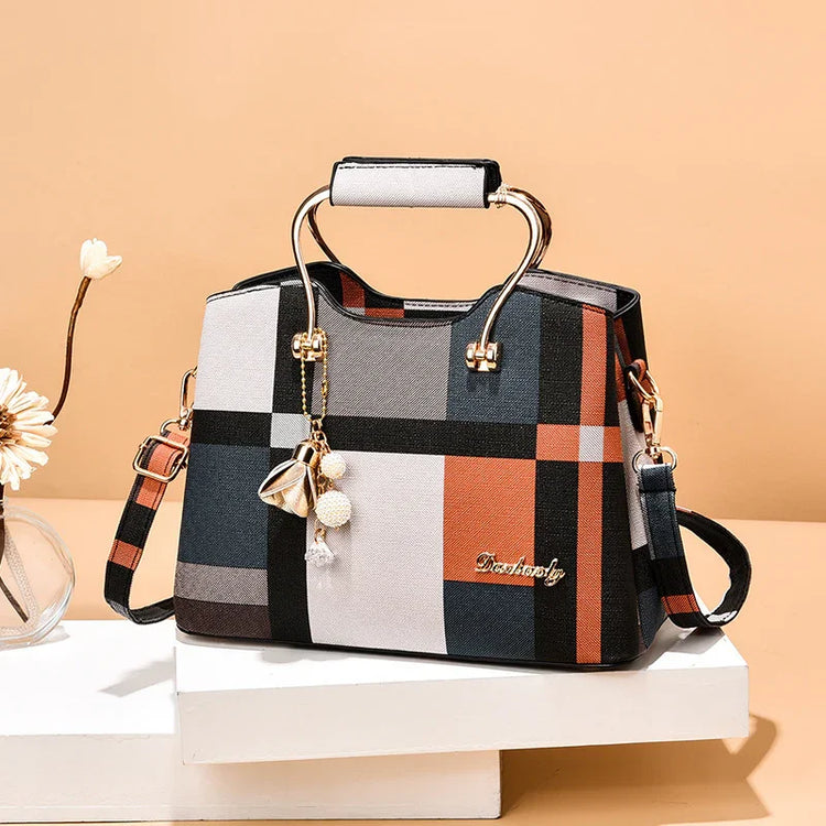 Plaid pattern handbag in orange, gray, and black tones with top handles and gold accents