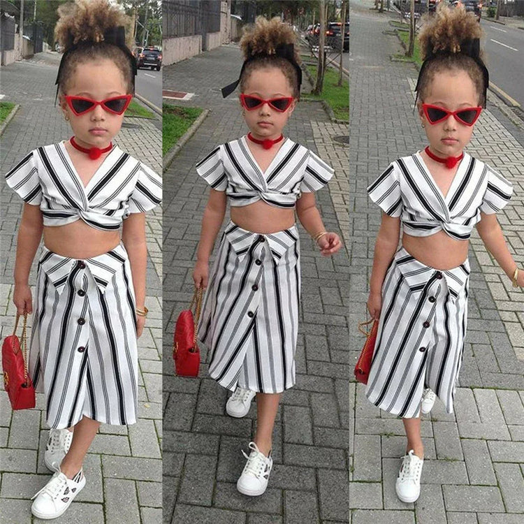 Girl in black and white striped crop top and button-front skirt, white sneakers, red accessories, street style