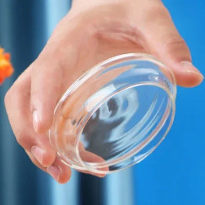 Hand holding a round clear glass dish, minimalist and transparent design
