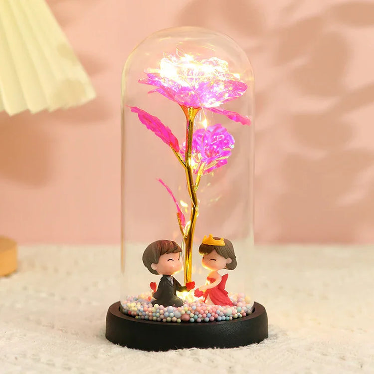 Glass dome with LED rose flower and romantic figurines, decorative pink lighting.