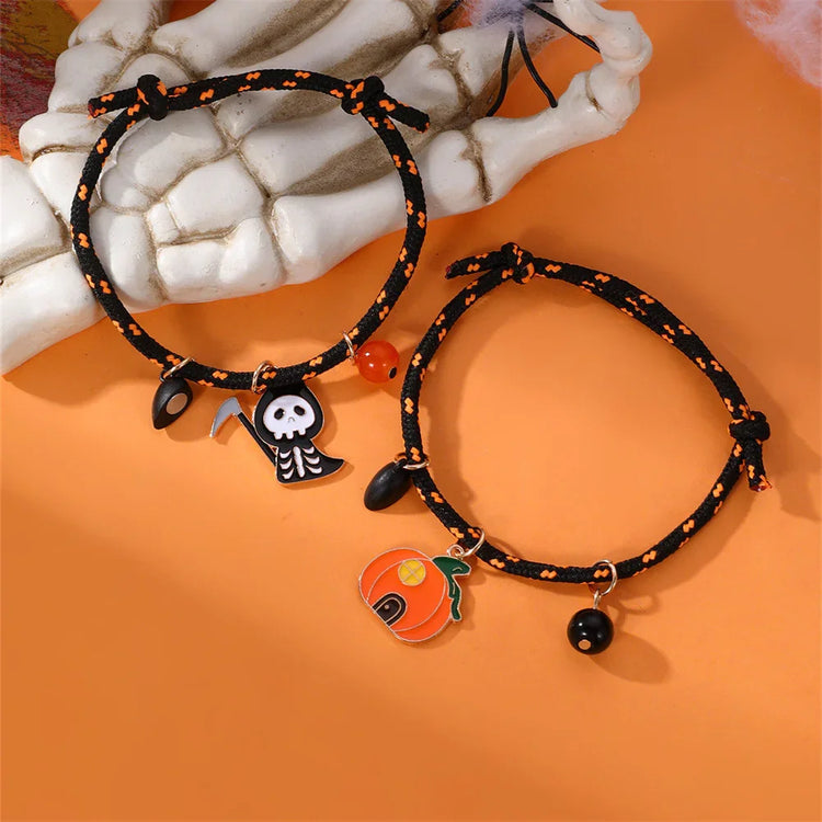 Black and orange woven Halloween bracelets with pumpkin and skeleton charms on orange background
