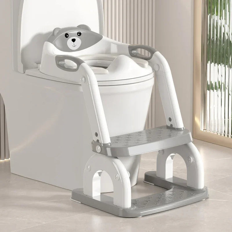 Gray and white plastic kids toilet training seat with bear design and step ladder on modern toilet.