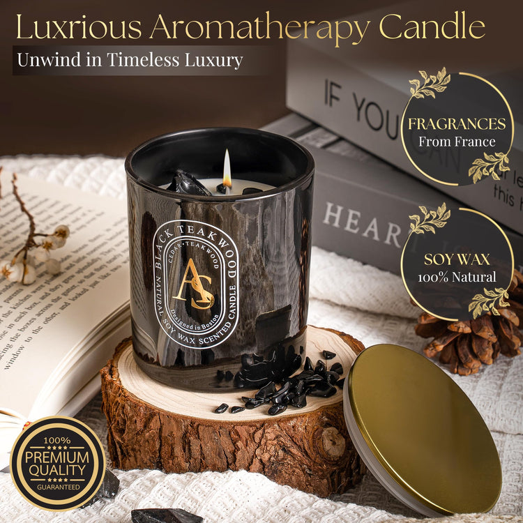 Black scented candle for men with obsidian crystals and teakwood scent in luxury glass jar with gold lid on wooden coaster