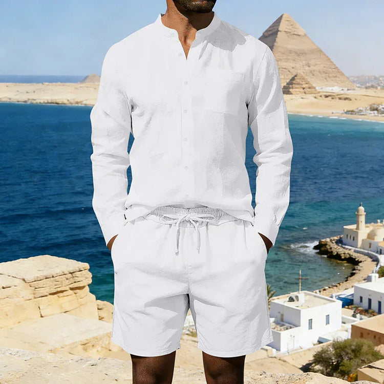 Man wearing a white linen long-sleeve shirt and drawstring shorts, relaxed fit, coastal background