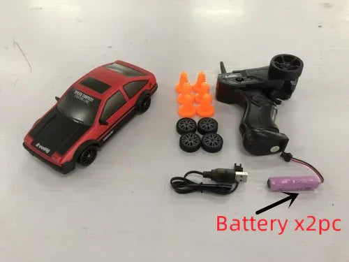 Red remote control drift car set with spare wheels, cones, controller, USB charger, and battery.
