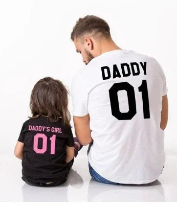 Man and child wearing matching family t-shirts, black and white, relaxed fit, bold lettering.