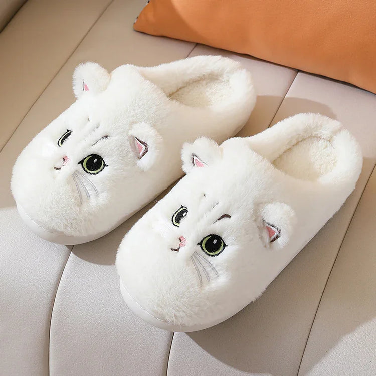 White plush slippers with cute cat face design, cozy indoor footwear on a couch