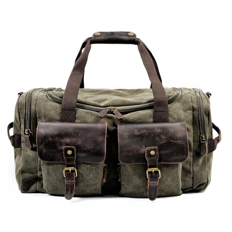 Olive green canvas duffel bag with brown leather pockets and adjustable straps