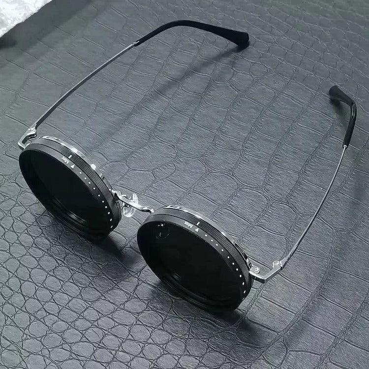 Futuristic round black sunglasses with metal frame on textured dark surface