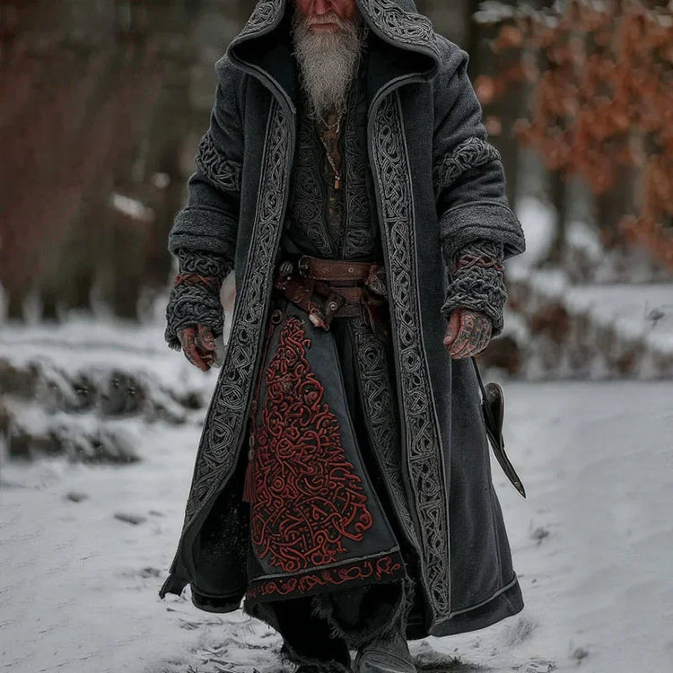 Man wearing long gray medieval-style coat with intricate patterns, layered winter outfit, relaxed fit.