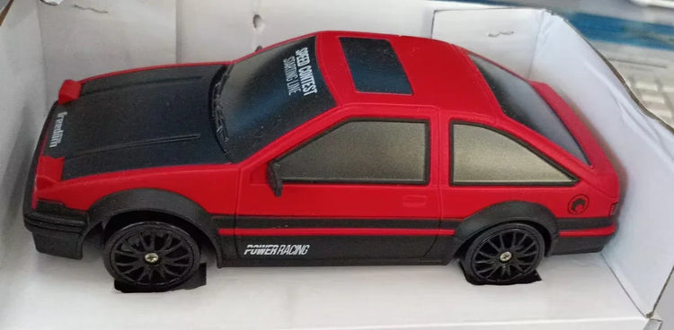 Red and black toy sports car with black wheels and racing decals, placed in packaging.