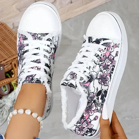 White low-top sneakers with black skull and pink floral print, lace-up, casual streetwear style