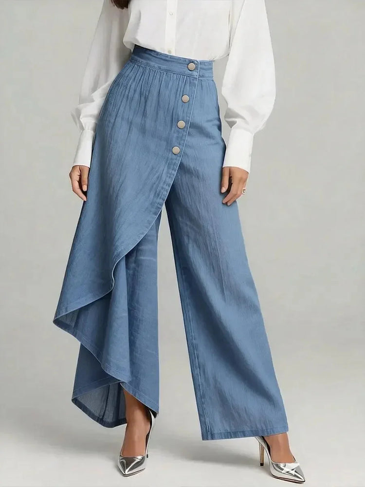 Woman wearing wide-leg blue denim pants with asymmetric wrap detail and a white blouse