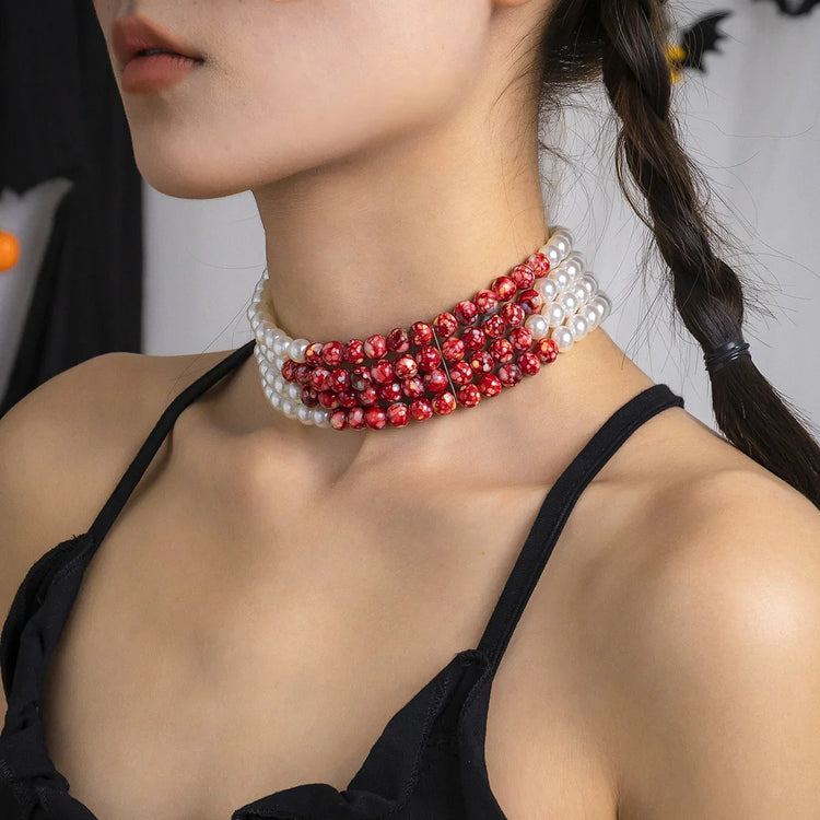 Woman wearing a layered pearl and red beaded choker, black strappy top, modern streetwear style