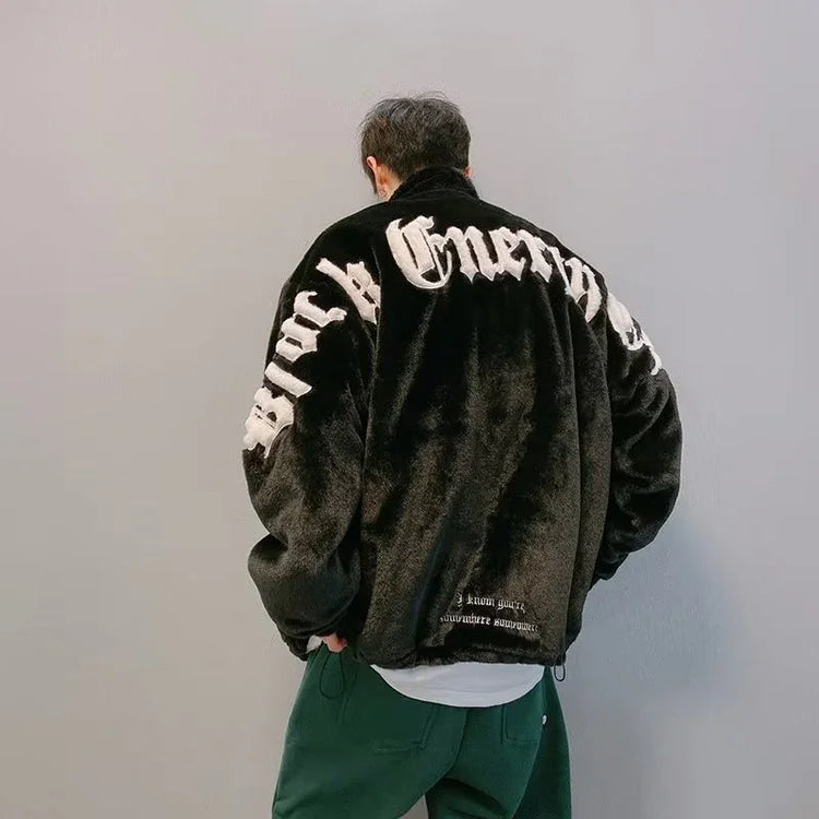 Man wearing oversized black faux fur jacket with bold white lettering, relaxed streetwear style