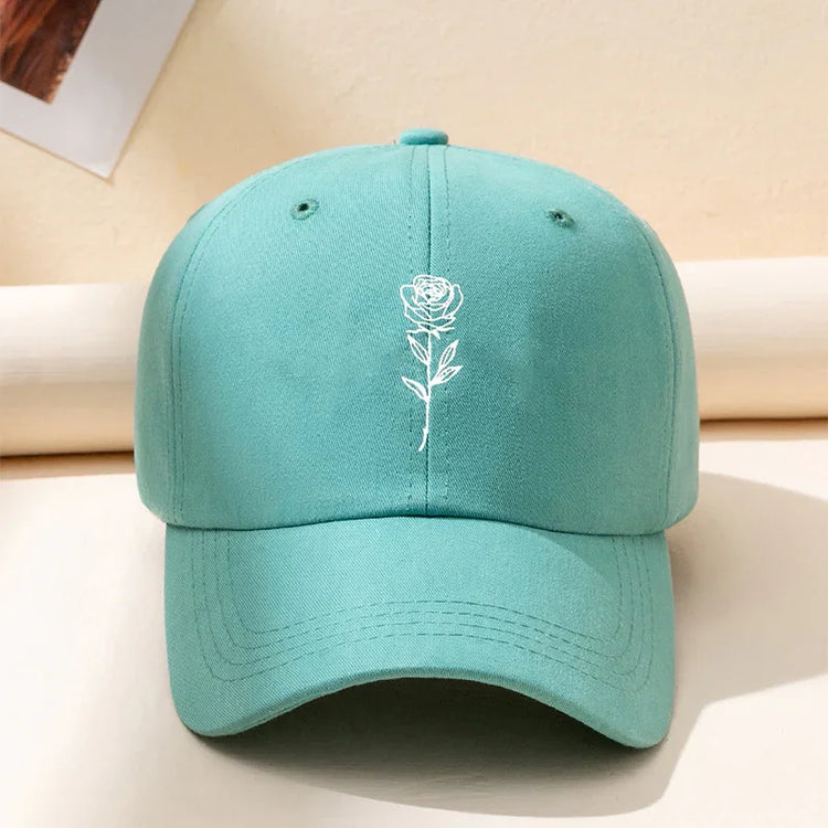 Aqua blue cotton baseball cap with white embroidered rose graphic, relaxed fit streetwear