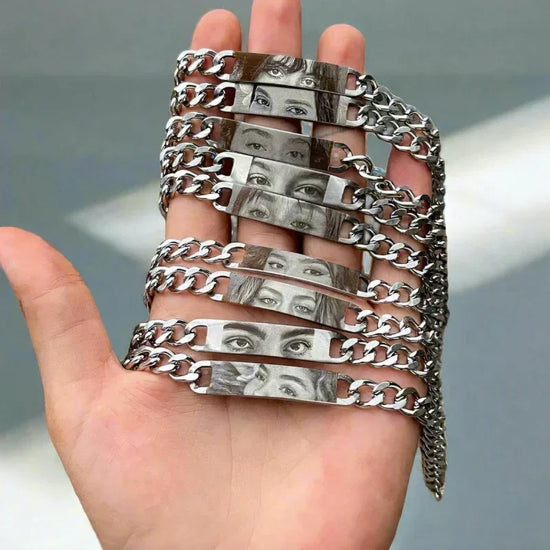 Silver metal chain bracelets with engraved artistic eye designs, displayed on a hand