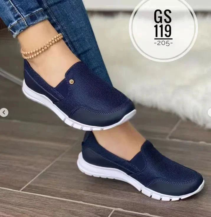 Navy blue mesh slip-on sneakers with white soles, casual fit, worn with jeans.