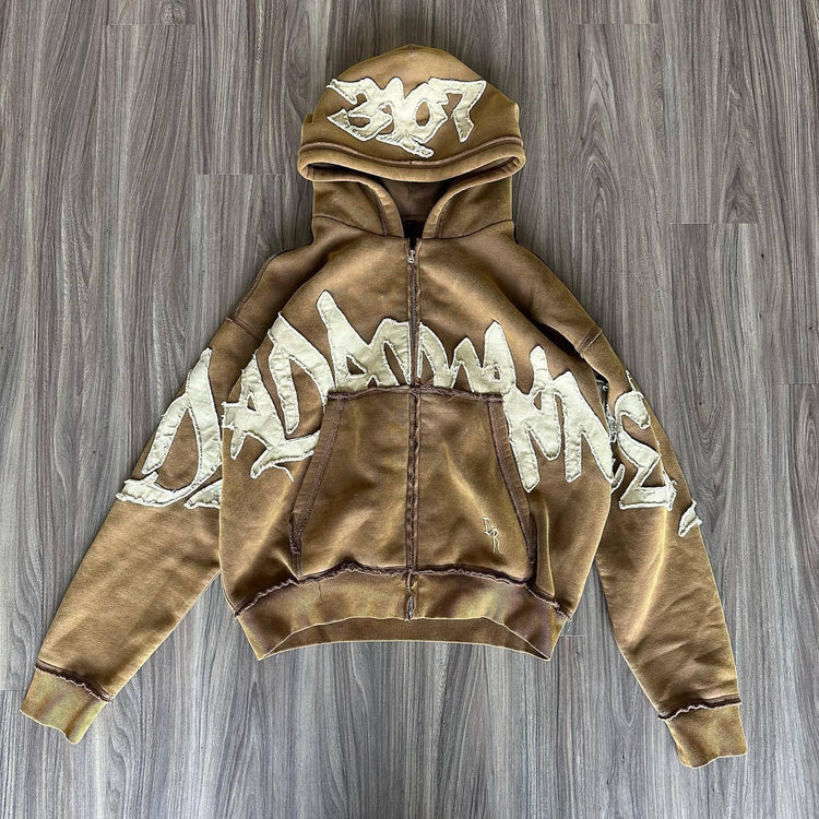 Brown oversized zip-up hoodie with bold white graffiti graphic, fleece material, relaxed fit