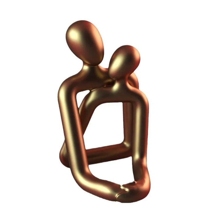 Abstract gold metallic sculpture of two stylized figures embracing on white background