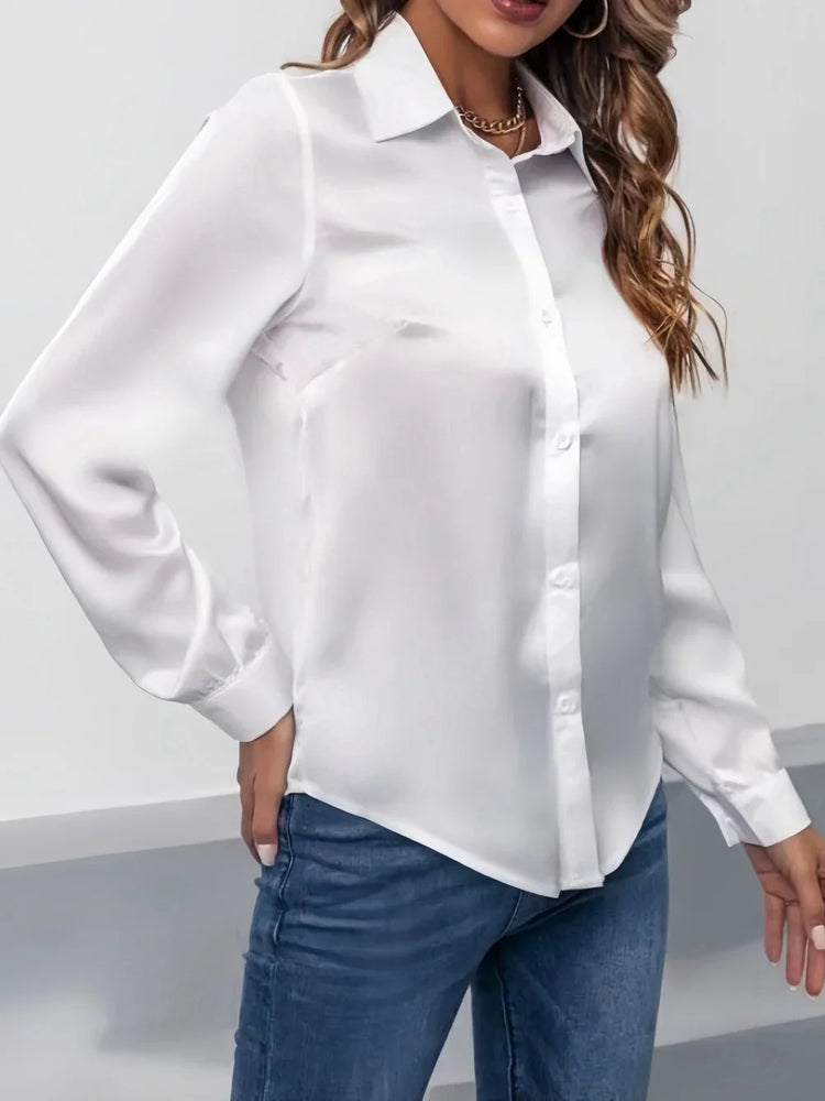 Woman wearing a white long sleeve button-up blouse with classic collar and blue jeans