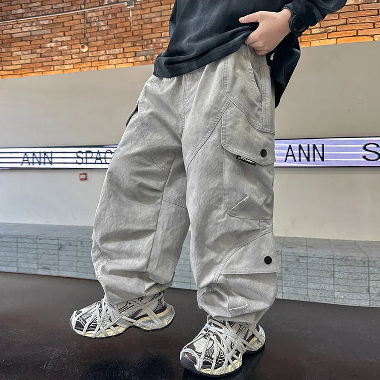 Loose fit gray cargo pants with oversized pockets and tech style, paired with chunky sneakers.