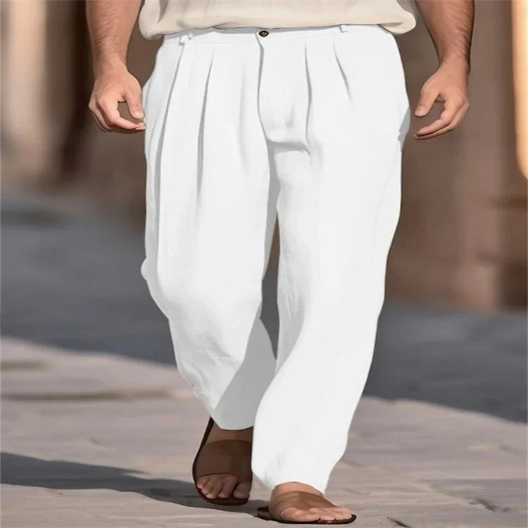 White linen pleated relaxed-fit trousers for men, styled with sandals outdoors