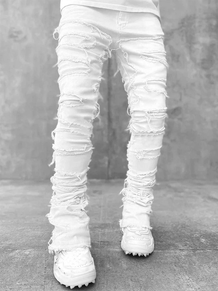 White distressed skinny jeans with heavy rips, paired with chunky white sneakers