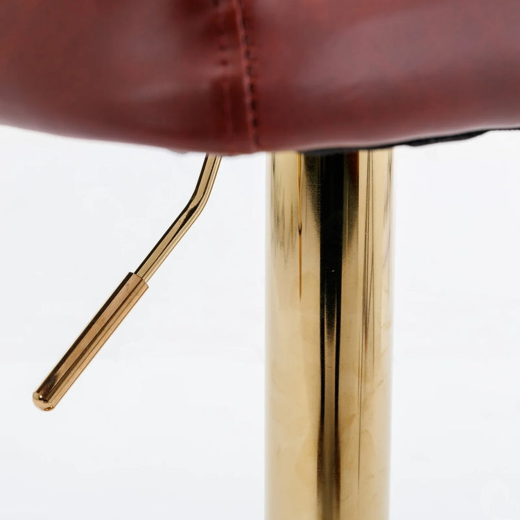 Close-up of brown leather upholstery with gold metal adjustable bar stool base