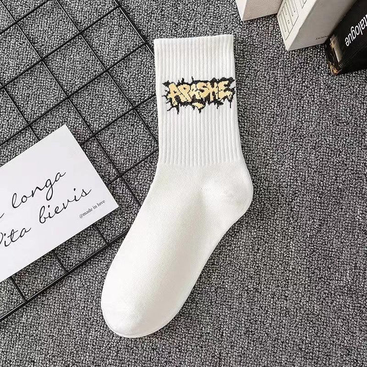 White crew sock with graffiti-style yellow and black logo, ribbed cotton, streetwear style
