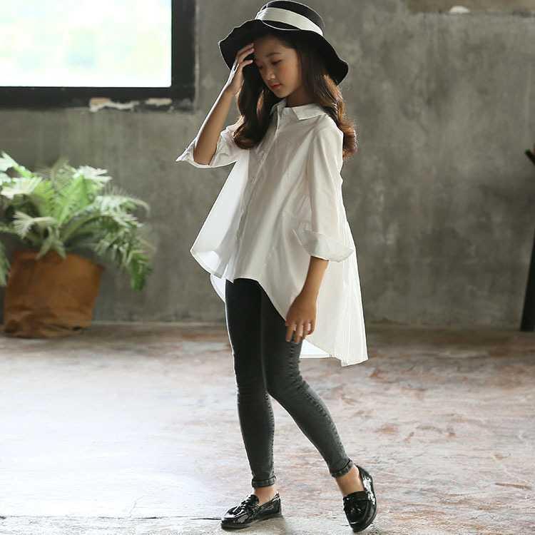 Girl wearing oversized white cotton shirt, black leggings, black hat, and loafers indoors