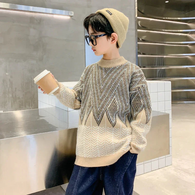 Child wearing oversized beige and grey geometric knit sweater, loose jeans, and ribbed beanie in modern indoor setting.