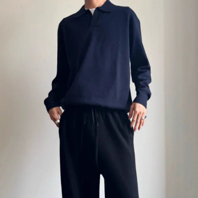 Man wearing a relaxed fit navy knit long sleeve polo shirt and black drawstring pants