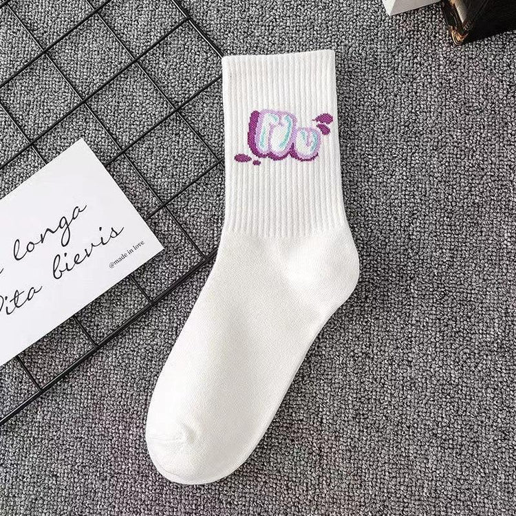 White ribbed crew sock with colorful graphic text detail, laid flat on grey carpet