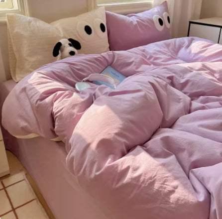 Soft pastel pink bedding with plush, cartoon eye-themed pillowcases in a cozy bedroom