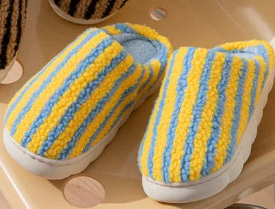 Cozy slip-on slippers with yellow and blue striped plush fleece, cushioned sole, relaxed fit.