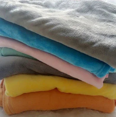 Stack of colorful fleece blankets in grey, blue, pink, yellow, and orange, soft texture