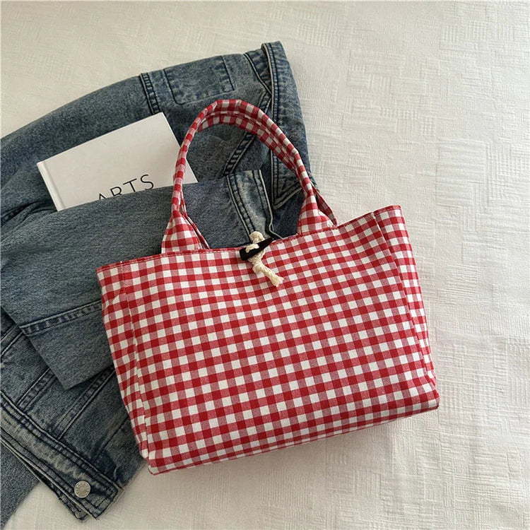 Red and white gingham tote bag with cotton rope closure, laid on a denim jacket
