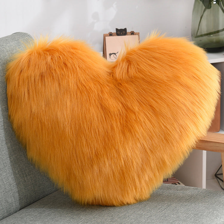 Fluffy orange faux fur heart-shaped pillow on a gray chair, cozy modern decor