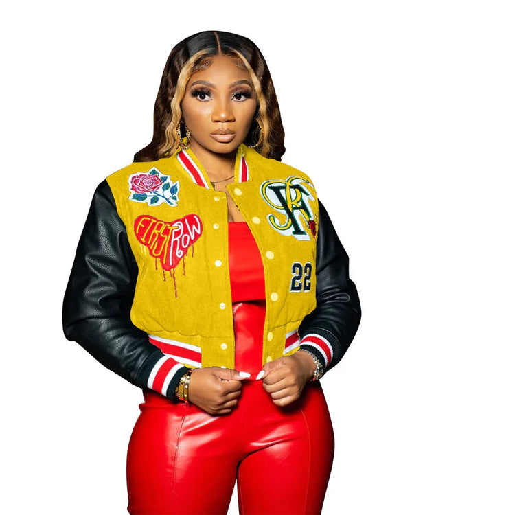 Woman wearing a yellow and black varsity jacket with patches, paired with red faux leather pants.