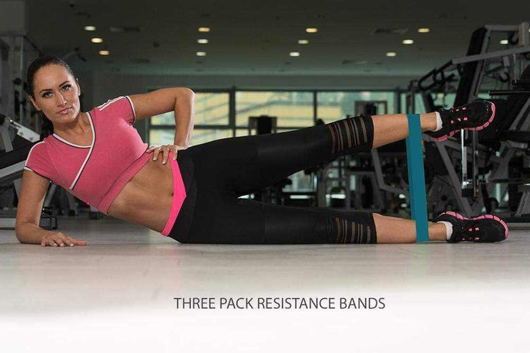 Woman in sporty pink crop top and black mesh leggings using resistance band at gym.