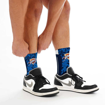Person wearing blue crew socks with graphic pattern and black-and-white sneakers