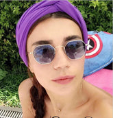 Woman wearing a purple turban headband and geometric sunglasses, outdoor setting
