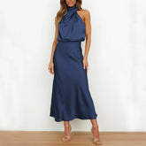 Woman wearing a navy blue satin halter neck midi dress with a relaxed fit.