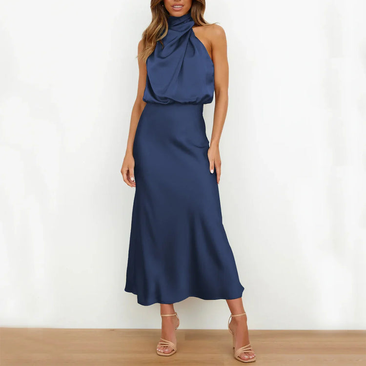 Woman wearing a navy blue satin halter neck midi dress with a relaxed fit.