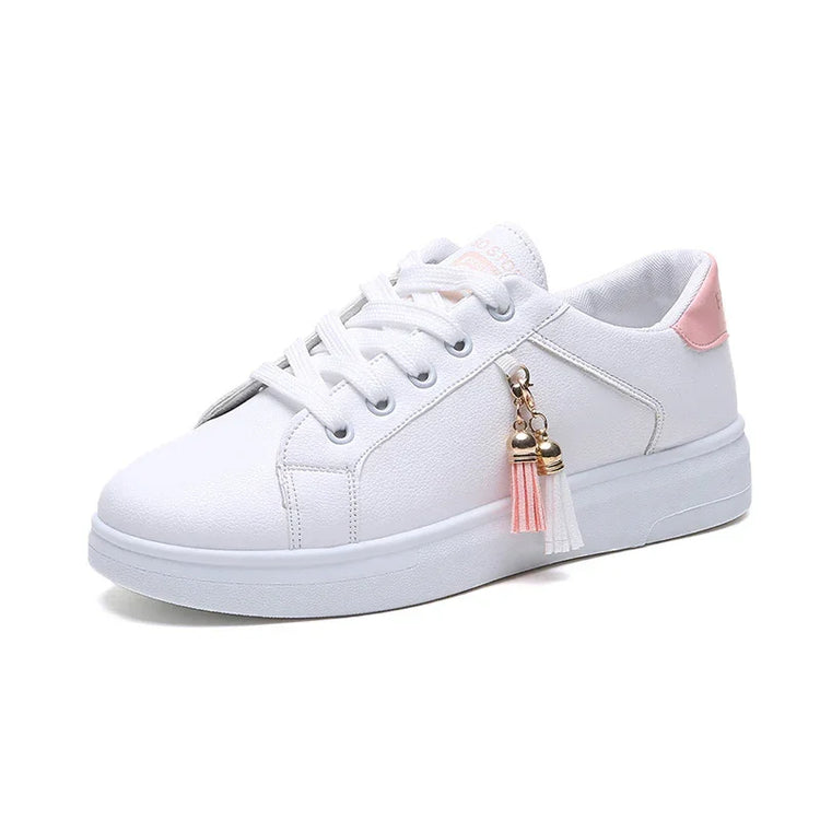 White low-top sneaker with pink heel accent, lace-up design, and tassel charm detail.